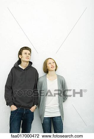 Young couple leaning against wall, looking up View Large Photo Image Stock Image - Young couple leaning against wall, looking up. Fotosearch