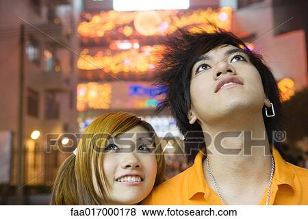 Stock Photo - Young couple, looking up, portrait. Fotosearch