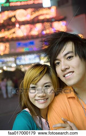 Stock Photo - Young couple, neon lights in background, portrait. Fotosearch
