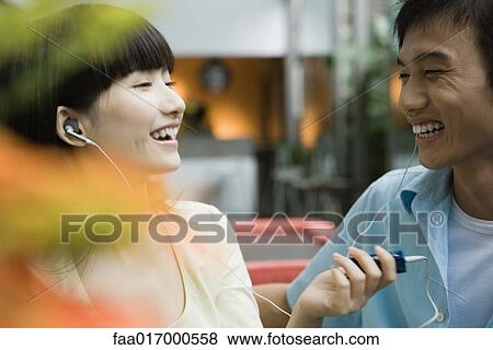 Young couple sharing earphones, laughing View Large Photo Image Stock Photo - Young couple sharing earphones, laughing. Fotosearch