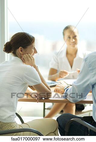 Stock Photo - Young couple sitting across table from young female professional. Fotosearch