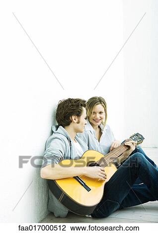 Young couple sitting on ground, man playing guitar View Large Photo Image Stock Image - Young couple sitting on ground, man playing guitar. Fotosearch