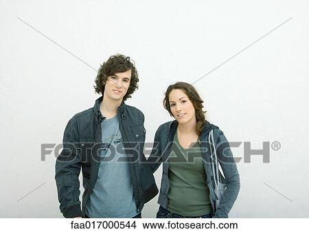 Young couple standing side by side, looking at camera, portrait, white background View Large Photo Image Picture - Young couple standing side by side, looking at camera, portrait, white background. Fotosearch