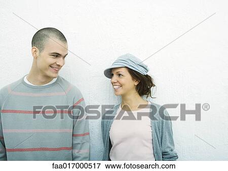 Stock Photo - Young couple standing side by side, portrait, white background. Fotosearch
