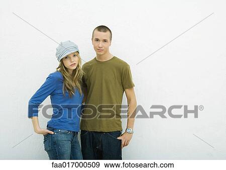 Young couple standing with hands in pockets, portrait, white background View Large Photo Image Stock Photo - Young couple standing with hands in pockets, portrait, white background. Fotosearch