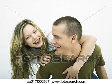 Stock Photo - Young couple, teenage girl on young man's back, white background. Fotosearch