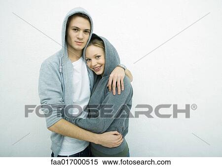 Young couple wearing hooded sweatshirts, embracing View Large Photo Image Stock Photography - Young couple wearing hooded sweatshirts, embracing. Fotosearch