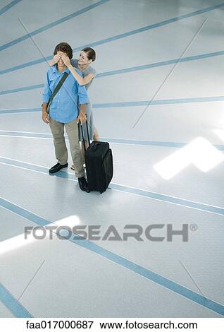 Young couple, woman standing behind boyfriend, covering his eyes, full length View Large Photo Image Stock Photo - Young couple, woman standing behind boyfriend, covering his eyes, full length. Fotosearch