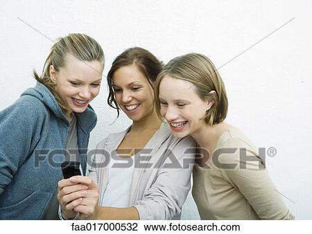 Young female friends looking at cell phone together View Large Photo Image Stock Image - Young female friends looking at cell phone together. Fotosearch