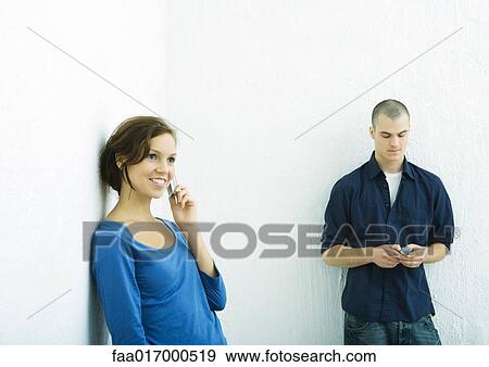 Young man and young woman using cell phones View Large Photo Image Stock Photo - Young man and young woman using cell phones. Fotosearch