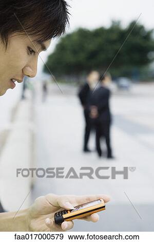 Young man looking at cell phone View Large Photo Image Stock Photo - Young man looking at cell phone. Fotosearch