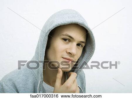 Young man scratching chin, wearing hood, portrait View Large Photo Image Stock Photograph - Young man scratching chin, wearing hood, portrait. Fotosearch
