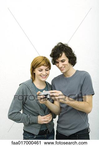 Stock Image - Young man showing young woman digital camera. Fotosearch