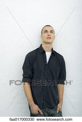 Young man standing looking up, hands in pockets, portrait View Large Photo Image Stock Image - Young man standing looking up, hands in pockets, portrait. Fotosearch