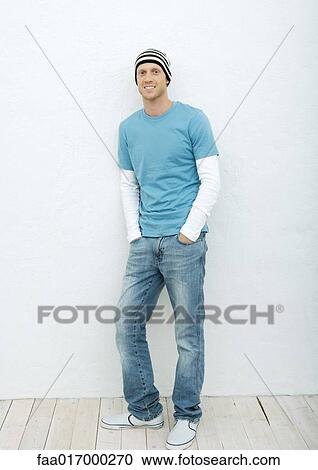 Stock Image - Young man standing with hands in pockets, full length portrait. Fotosearch