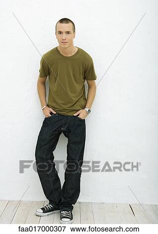Stock Photo - Young man standing with hands in pockets, full length portrait. Fotosearch