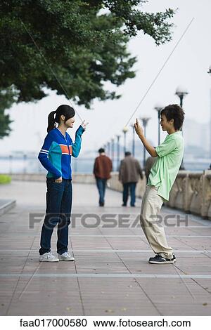 Stock Image - Young man taking photo of female friend. Fotosearch