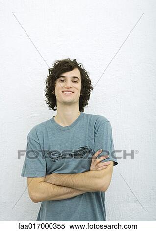 Young man with arms crossed, smiling at camera, portrait, white background View Large Photo Image Stock Photography - Young man with arms crossed, smiling at camera, portrait, white background. Fotosearch