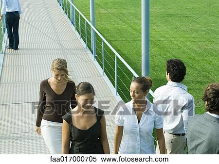 Stock Photography - Young professionals walking and standing on walkway. Fotosearch