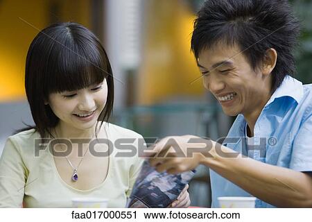 Young woman and young man looking at document together View Large Photo Image Stock Image - Young woman and young man looking at document together. Fotosearch