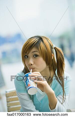 Young woman drinking fast food drink, looking at camera View Large Photo Image Stock Image - Young woman drinking fast food drink, looking at camera. Fotosearch