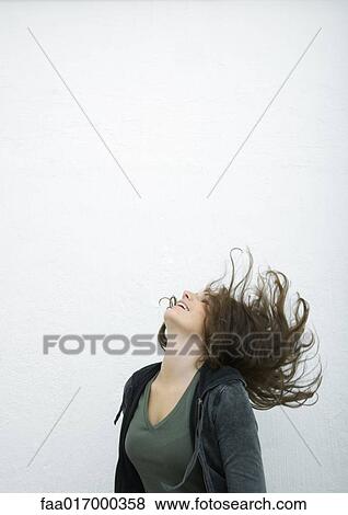 Stock Photo - Young woman flipping hair back, white background. Fotosearch