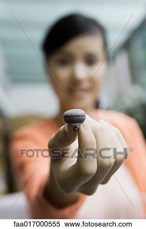 Young woman holding up earphone, focus on hand in foreground View Large Photo Image Stock Photography - Young woman holding up earphone, focus on hand in foreground. Fotosearch