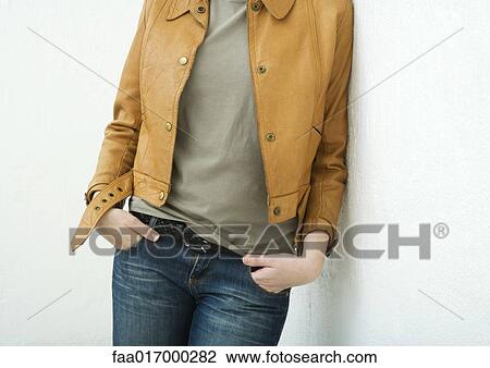 Young woman leaning against wall, mid-section View Large Photo Image Stock Image - Young woman leaning against wall, mid-section. Fotosearch