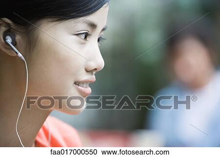 Young woman listening to earphones View Large Photo Image Stock Image - Young woman listening to earphones. Fotosearch