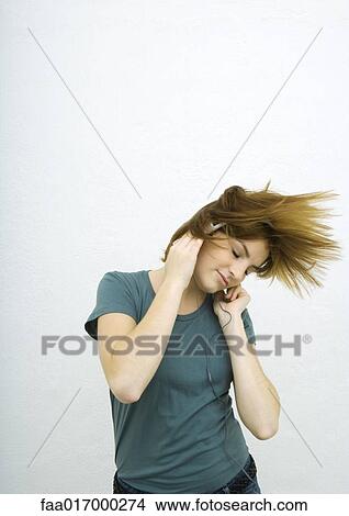 Young woman listening to headphones with eyes closed, swinging hair View Large Photo Image Picture - Young woman listening to headphones with eyes closed, swinging hair. Fotosearch