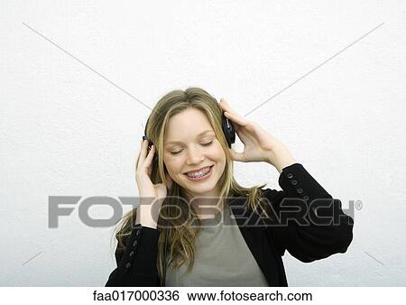 Young woman listening to headphones, eyes closed View Large Photo Image Stock Photograph - Young woman listening to headphones, eyes closed. Fotosearch