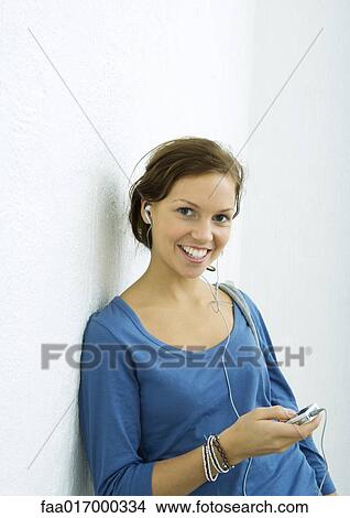 Picture - Young woman listening to MP3 player, portrait. Fotosearch