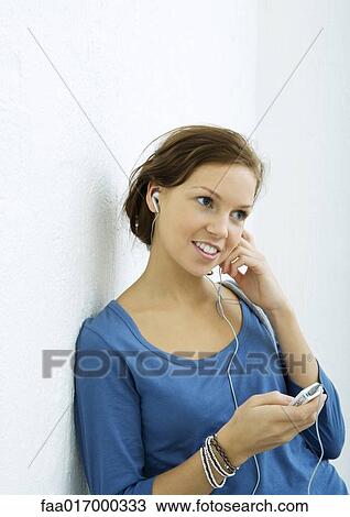 Young woman listening to MP3 player, portrait View Large Photo Image Stock Image - Young woman listening to MP3 player, portrait. Fotosearch