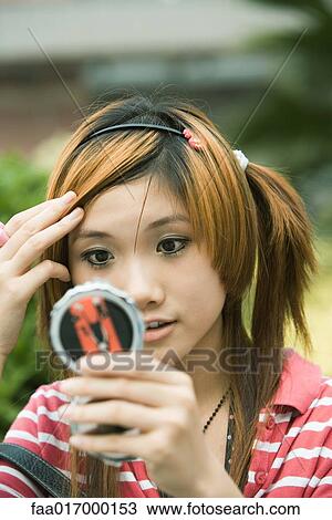 Young woman looking at self in pocket mirror View Large Photo Image Stock Image - Young woman looking at self in pocket mirror. Fotosearch