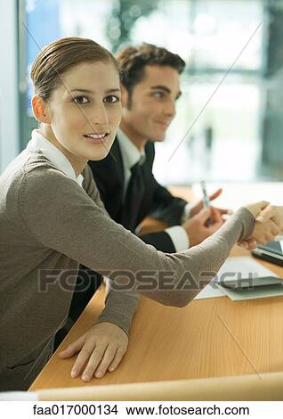 Young woman shaking hands across table, smiling at camera View Large Photo Image Picture - Young woman shaking hands across table, smiling at camera. Fotosearch