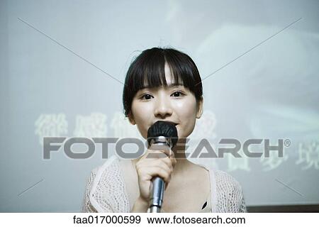Stock Photo - Young woman singing karaoke. Fotosearch
