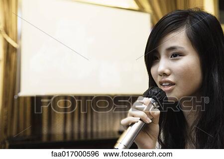 Young woman singing karaoke View Large Photo Image Stock Photograph - Young woman singing karaoke. Fotosearch