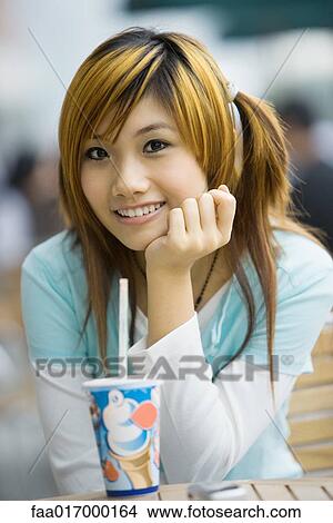 Young woman sitting with fast food drink, smiling at camera View Large Photo Image Picture - Young woman sitting with fast food drink, smiling at camera. Fotosearch