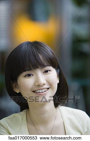 Stock Image - Young woman smiling at camera, portrait. Fotosearch