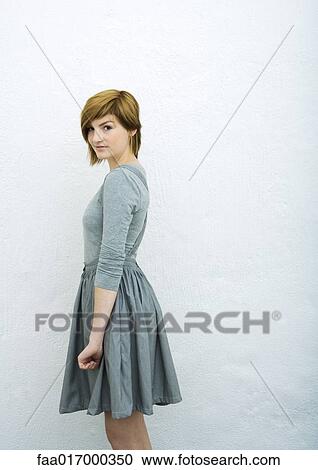 Young woman standing, looking at camera, side view, portrait View Large Photo Image Stock Image - Young woman standing, looking at camera, side view, portrait. Fotosearch