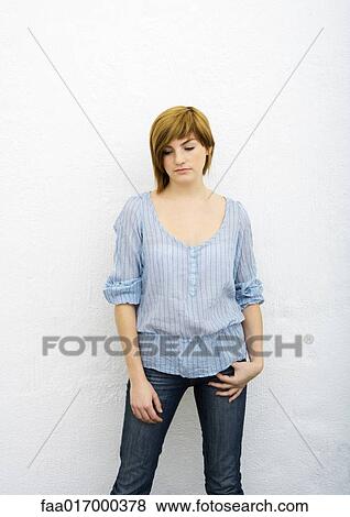 Stock Photo - Young woman standing, looking down, portrait, three quarter length. Fotosearch
