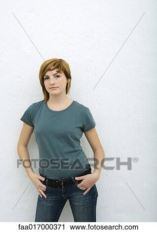 Young woman standing with hands in pockets, portrait View Large Photo Image Stock Image - Young woman standing with hands in pockets, portrait. Fotosearch