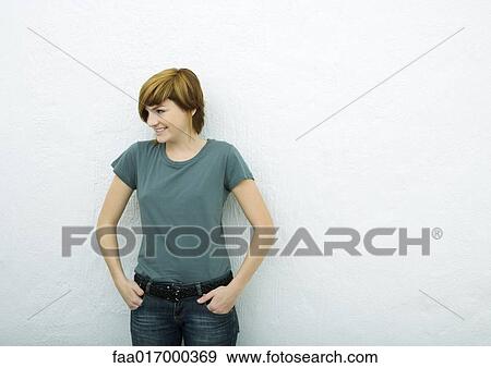 Young woman standing with hands in pockets, looking away, white background View Large Photo Image Stock Photo - Young woman standing with hands in pockets, looking away, white background. Fotosearch
