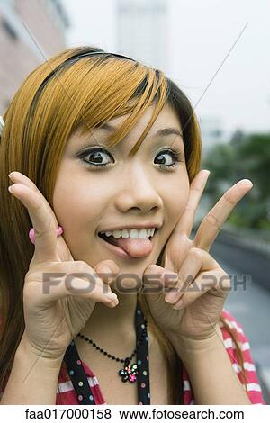 Young woman sticking out tongue at camera View Large Photo Image Stock Photo - Young woman sticking out tongue at camera. Fotosearch