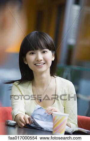 Young woman turning pages of book, smiling at camera View Large Photo Image Picture - Young woman turning pages of book, smiling at camera. Fotosearch