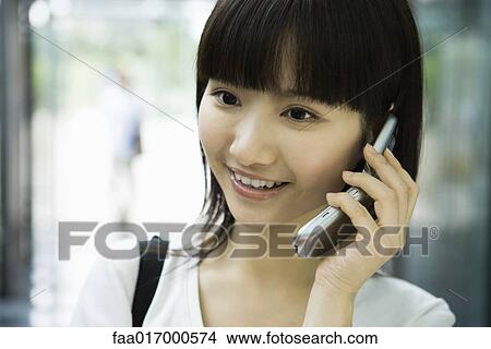 Young woman using cell phone, smiling View Large Photo Image Picture - Young woman using cell phone, smiling. Fotosearch