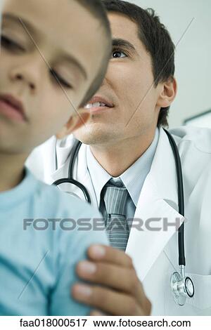 Stock Photo - Boy and doctor, doctor holding boy's shoulder, low angle view. Fotosearch