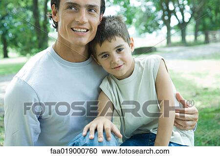 Stock Image - Boy and father, boy sitting on man's lap. Fotosearch