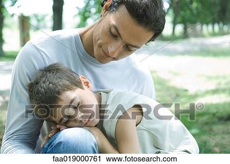 Stock Image - Boy and father, boy sleeping in man's lap. Fotosearch
