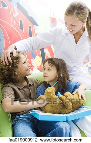 Boy and girl playing doctor with teddy bear while nurse watches View Large Photo Image Stock Image - Boy and girl playing doctor with teddy bear while nurse watches. Fotosearch